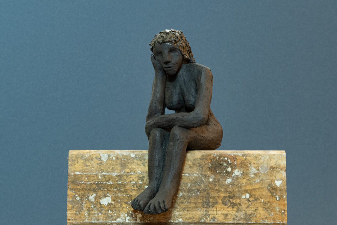 kleine skulptur einer sitzenden Frau aus Ton gebrannt.
