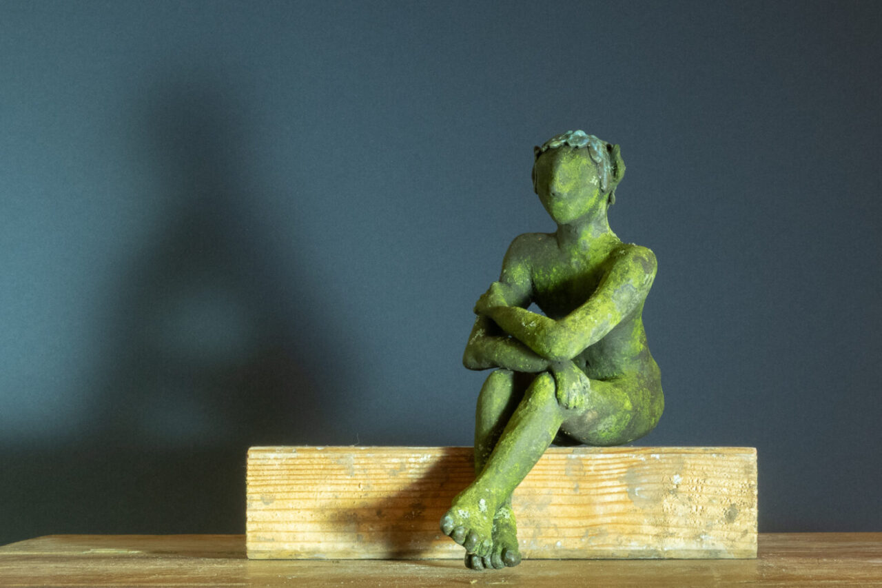 kleine skulptur eines sitzeden Mannes aus Ton gebrannt.