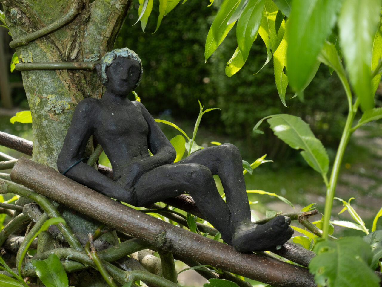 Skulptur eines sitzenden Mannes in einem Busch